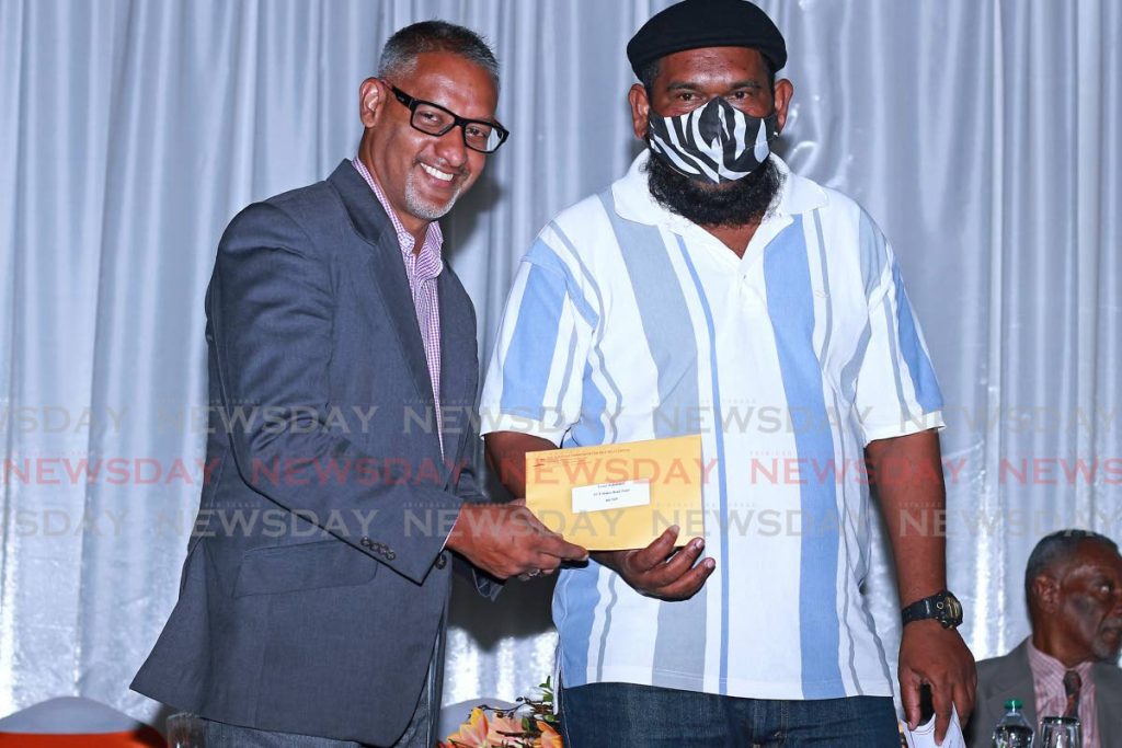 HELPING HAND: PNM Chaguanas East general election candidate Clarence Rambharat gives a grant to Fyzool Mohammed on Tuesday at a grant distribution ceremony held by the National Commissioner for Self Help at City Hall in San Fernando.  - CHEQUANA WHEELER
