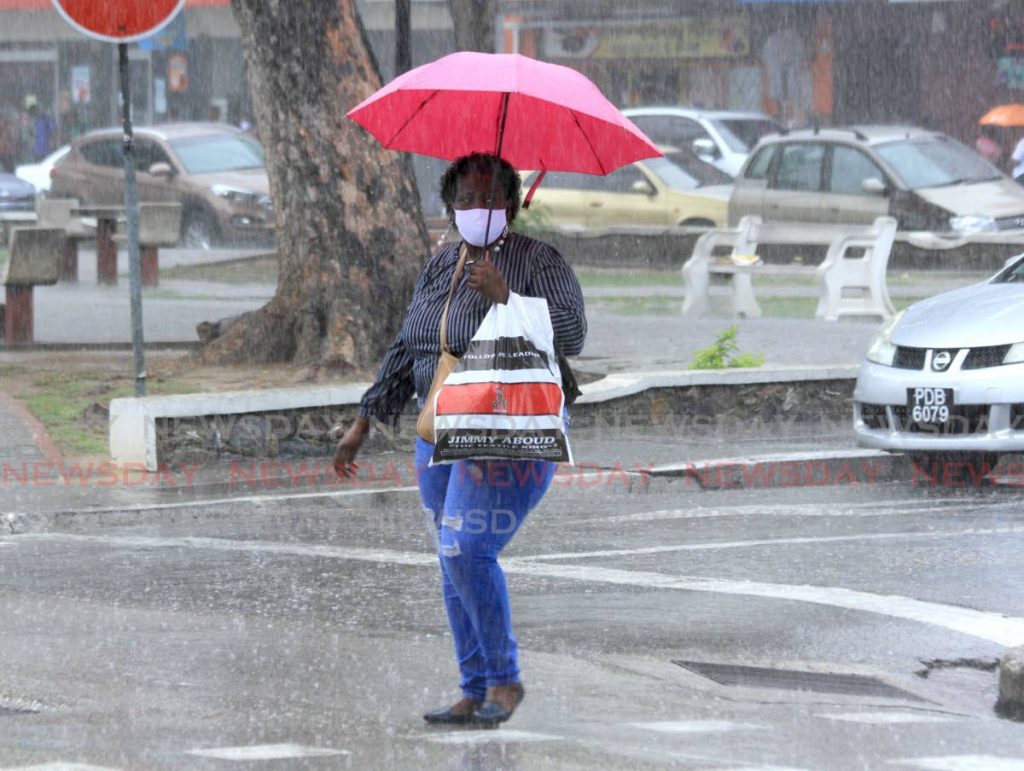 File photo - This lady shelters the rain with her umbrella while walking on Independence Square, Port of Spain. - Ayanna Kinsale