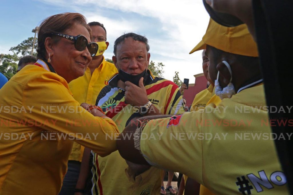 Kamla Persad-Bissessar, political leader of the UNC, greets a supporter during a motorcade on Wednesday in support of San Fernando West candidate Sean Sobers. Looking on is Pointe-a-Pierre candidate David Lee. - Marvin Hamilton