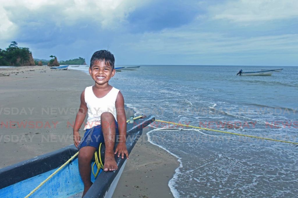 Three-year-old Caleb Harrypersad smiles brightly as he poses at the end of a boat at Gran Chemin Beach, Moruga, on Monday afternoon. - CHEQUANA WHEELER