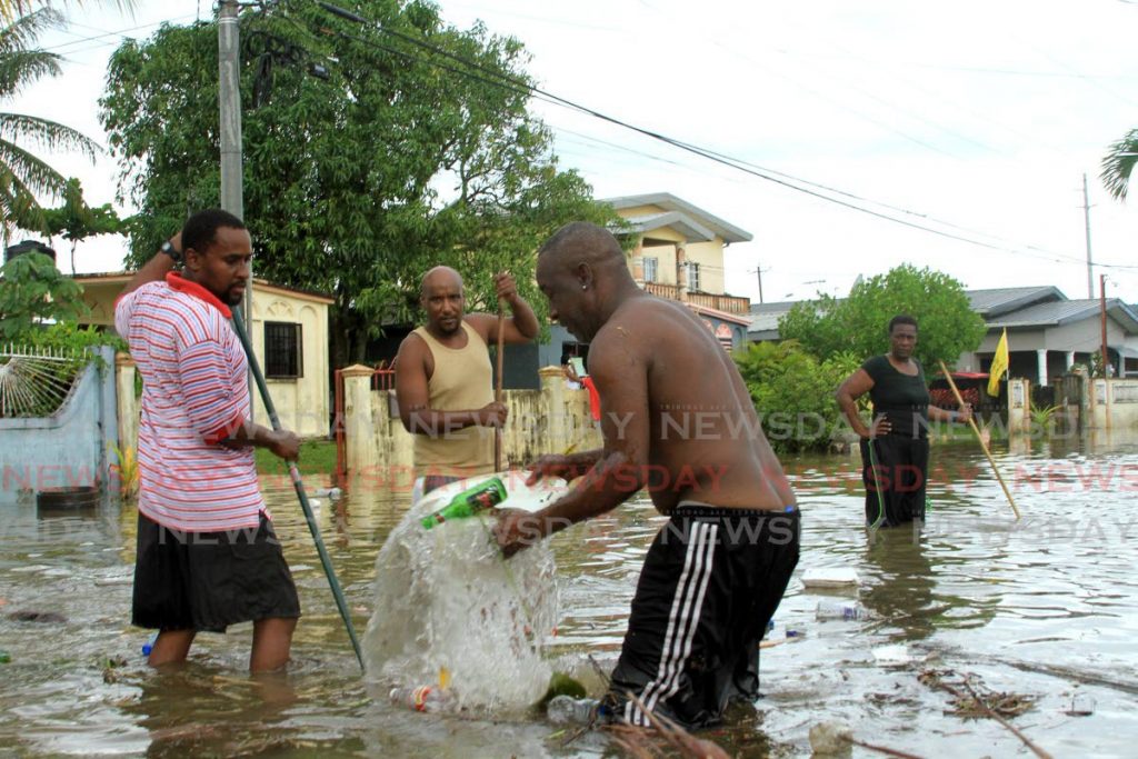 Residents of Ladybird Street in La Horquetta remove debris from the clogged drains. - Ayanna Kinsale