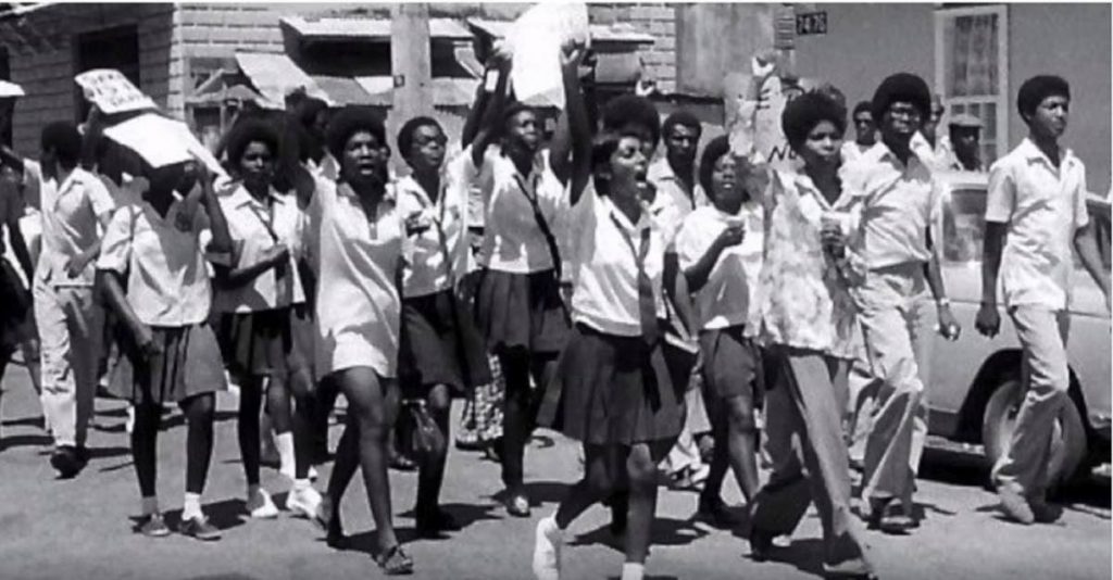 Protesting NORS students, including Josanne Leonard, Cynthia Evelyn (later Reverend Onika Grainger), and Lynette Patrick (later Ayesha Mutope) in Bishop Anstey High School uniform,march down Nelson Street. Photo by Apoesha Mutope courtesy Aiyegoro Ome - 