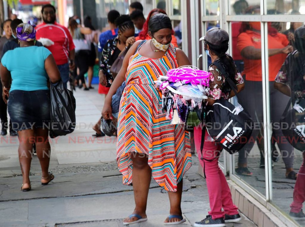 A vendor offers face masks to a woman on Frederick Street, Port of Spain. - SUREASH CHOLAI