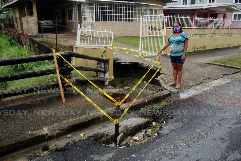 Maala Boodhu-Latchman points to the damaged pavement and driveway in front of her home on Tiara Boulevard, off Wendy Fitzwilliam Boulevard, Diamond Vale, Diego Martin on Wednesday.


 - SUREASH CHOLAI