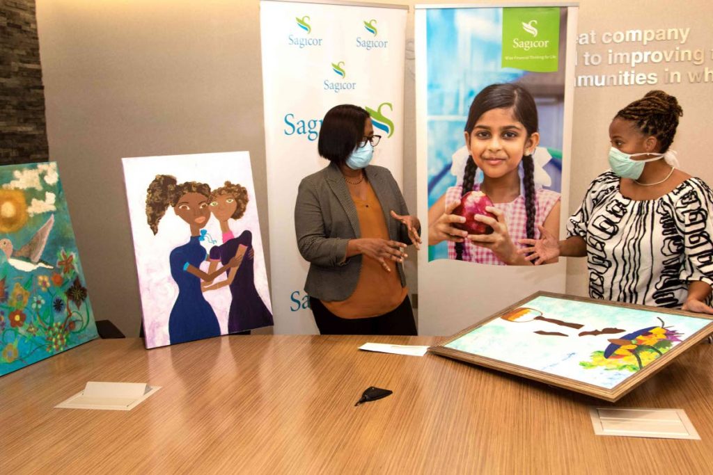 Michelle Bell-Sookhoo, left, Sagicor’s assistant vice president, human resources, discusses the impact of the Chosen Hands Art and Wellness Programme with its founder and creative director Anika Plowden-Corentin. In the photo, work by Hope Mc Nish and Nadia Charles is on display.  - 