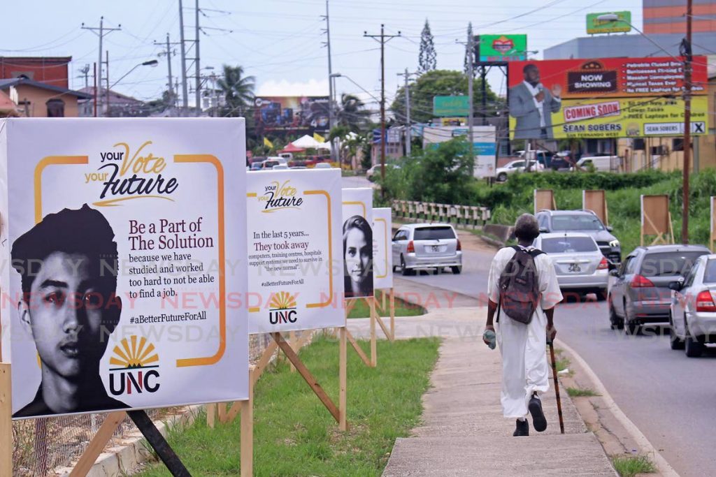 A man walks past a line of UNC billboards on Gulf View Link Road, San Fernando on Thursday.  - CHEQUANA WHEELER