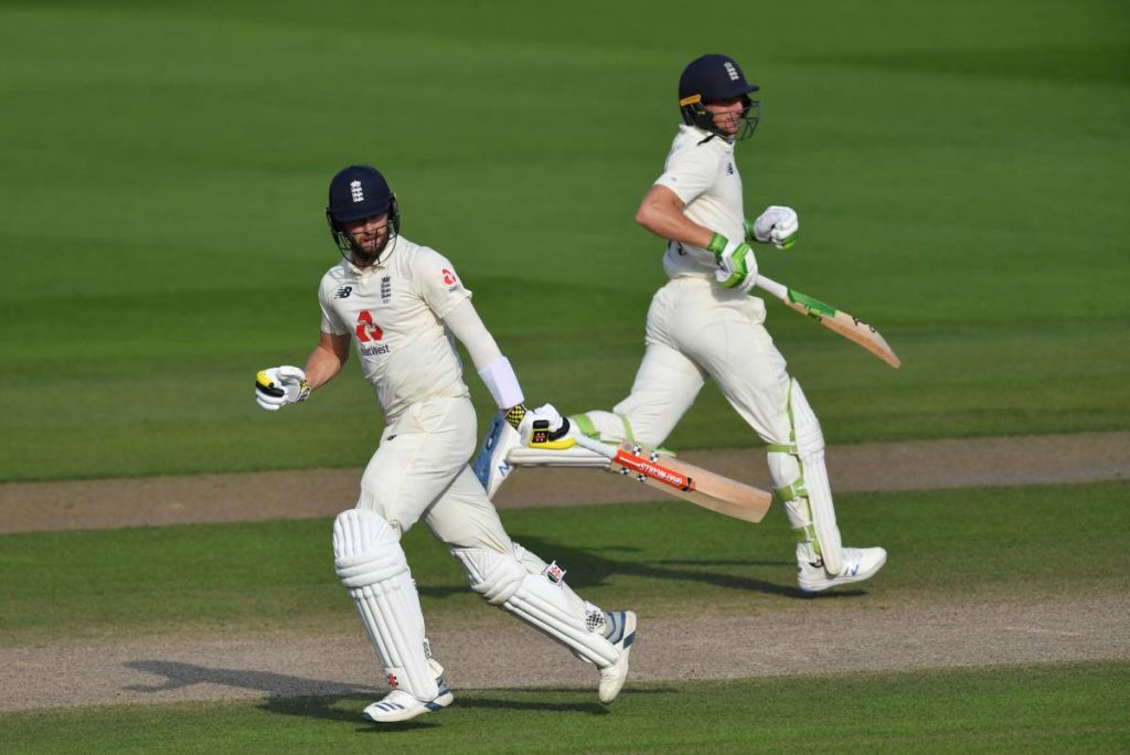 England’s Chris Woakes (left), and Jos Buttler run between the wickets to score during the fourth day of the first Test match between England and Pakistan at Old Trafford in Manchester, England, on Saturday. AP PHOTO - 