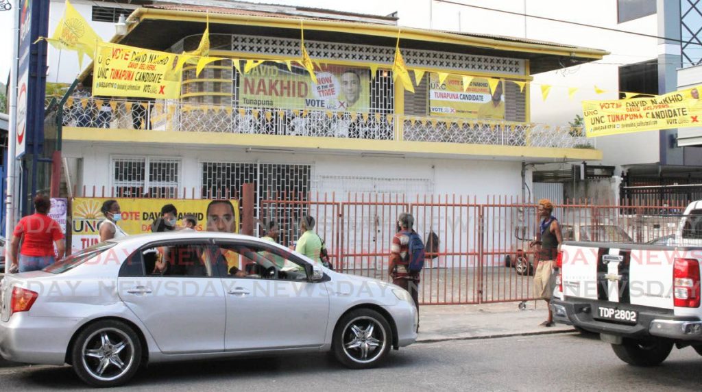 UNC campaign workers stand outside the chain locked gates to the El Dorado, Eastern Main Road, campaign office of UNC's Tunapuna candidate in Monday's general election David Nakhid. - Angelo Marcelle