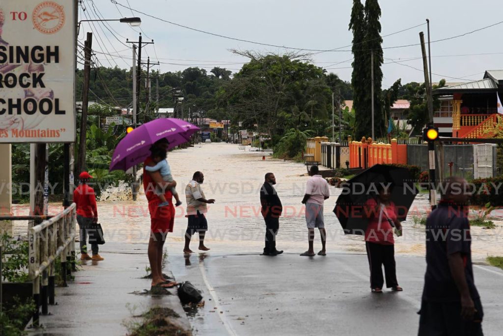 Residents gather at the edge of the flood water on Penal Rock Road on Tuesday. - Lincoln Holder