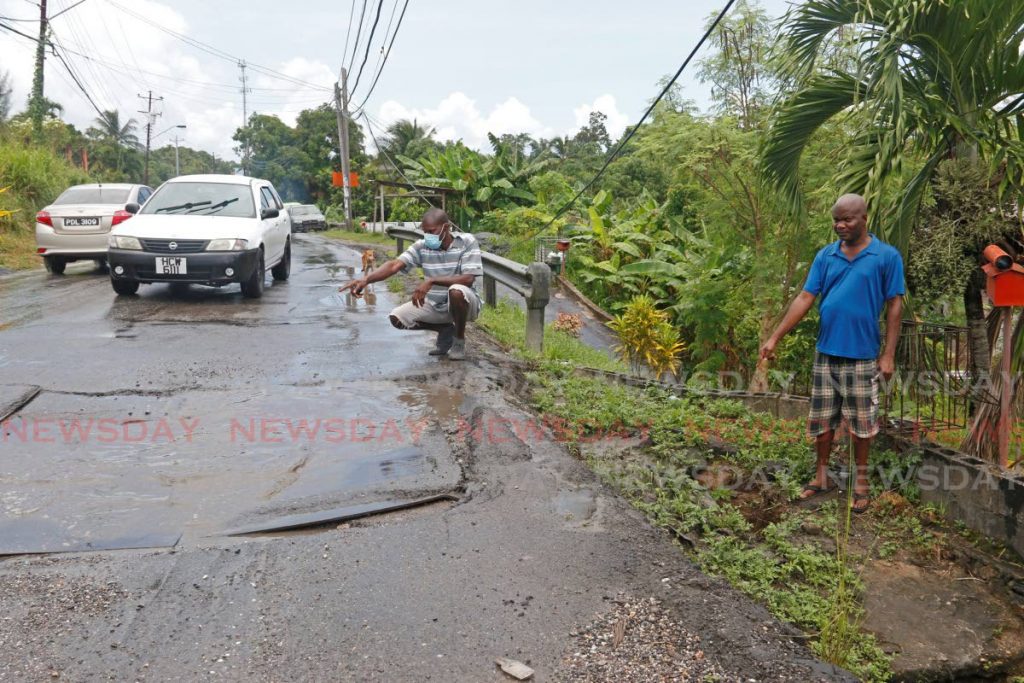 Peter Mitchell (in blue T-shirt) and Nigel Williams, both  of SS Erin Road, Penal, look at the metal sheets placed over a damaged cylinder close to their homes. - Marvin Hamilton