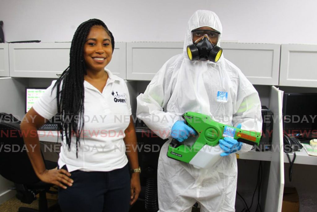 Jenna Neaves, owner of Squeeky Queens sanitisation company, alongside Andell Francois, a sanitisation technician and owner of Compound General Contracting Ltd (CGC), in his PPE suit at an office in Port of Spain. PHOTOS BY ROGER JACOB - 