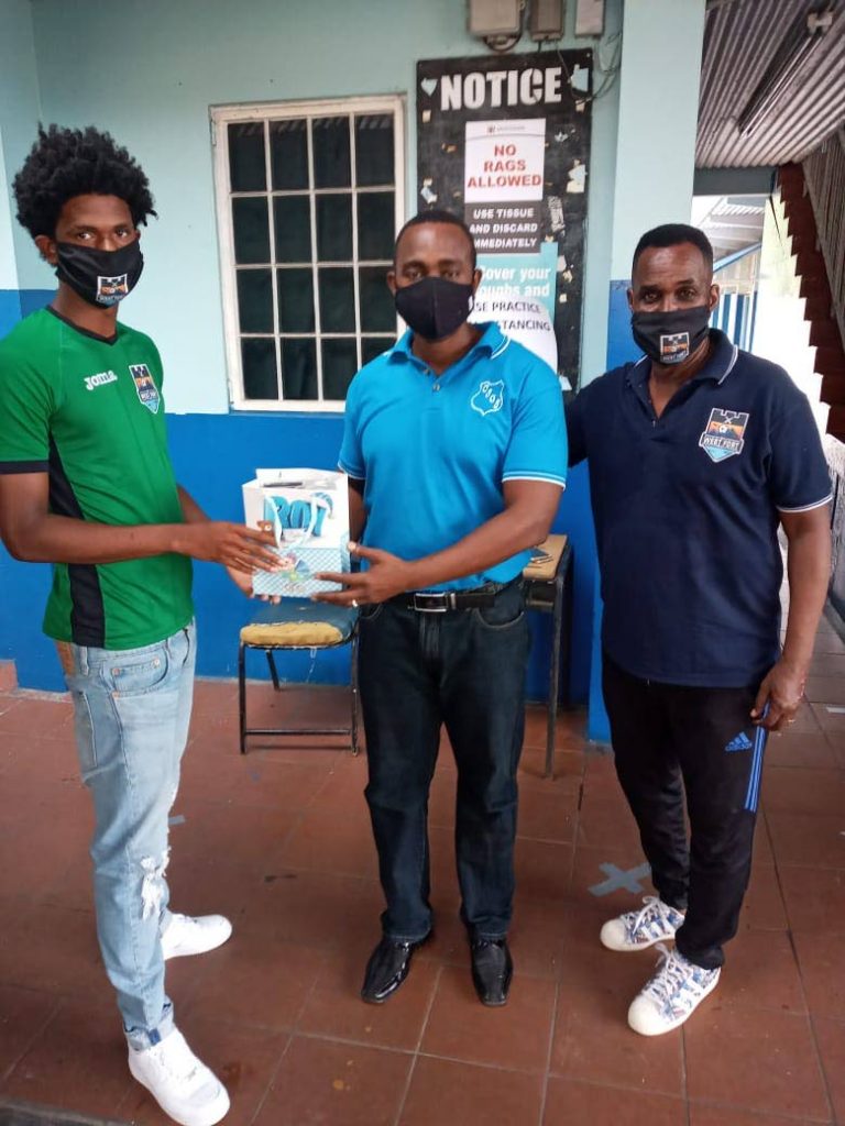 Real West Fort United and national pool player Jahiem Mc Fee, left, presents a Crystal Stream Government Primary School teacher with protective masks for SEA students. At right is club technical director Ron La Forest - 