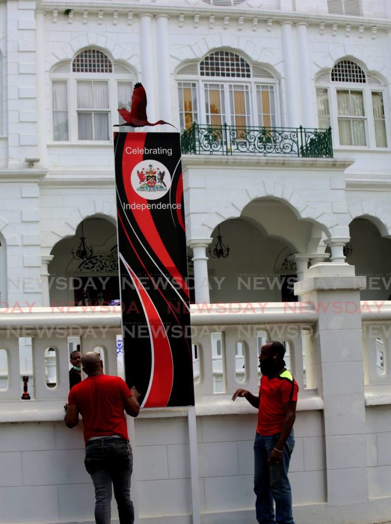 Workers place banners to mark TT's upcoming celebration of Independence Day at the Office of the Prime Minister, Queen's Park Savannah, Port of Spain, on Sunday. - SUREASH CHOLAI