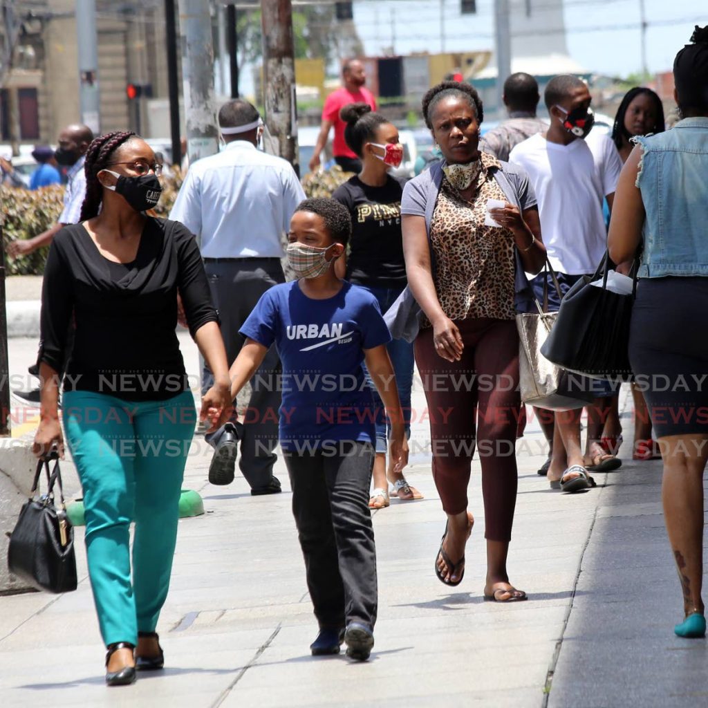 Pedestrians, some unmasked, walk along a street in Port of Spain recently. Parliament passed legislation which makes it illegal to be in public without a mask on. - SUREASH CHOLAI