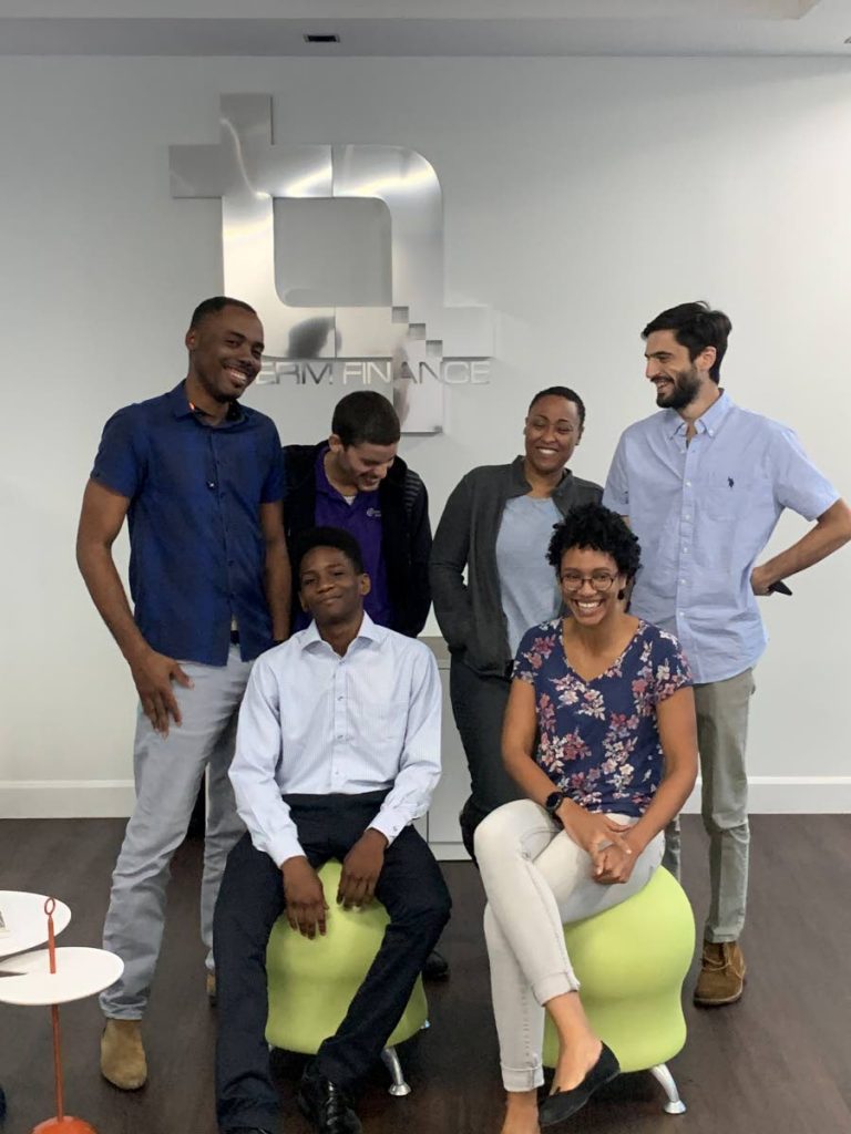 In this January file photo, 17-year-old Pleasantville Secondary School student Yohance Rivas (seated, left) is surrounded by staff of Term Finance as he begins a scholarship at the company. The budding entrepreneur earned an open one-year internship from CEO Oliver Sabga after the two interacted at a TecYOUth event the previous November. - 