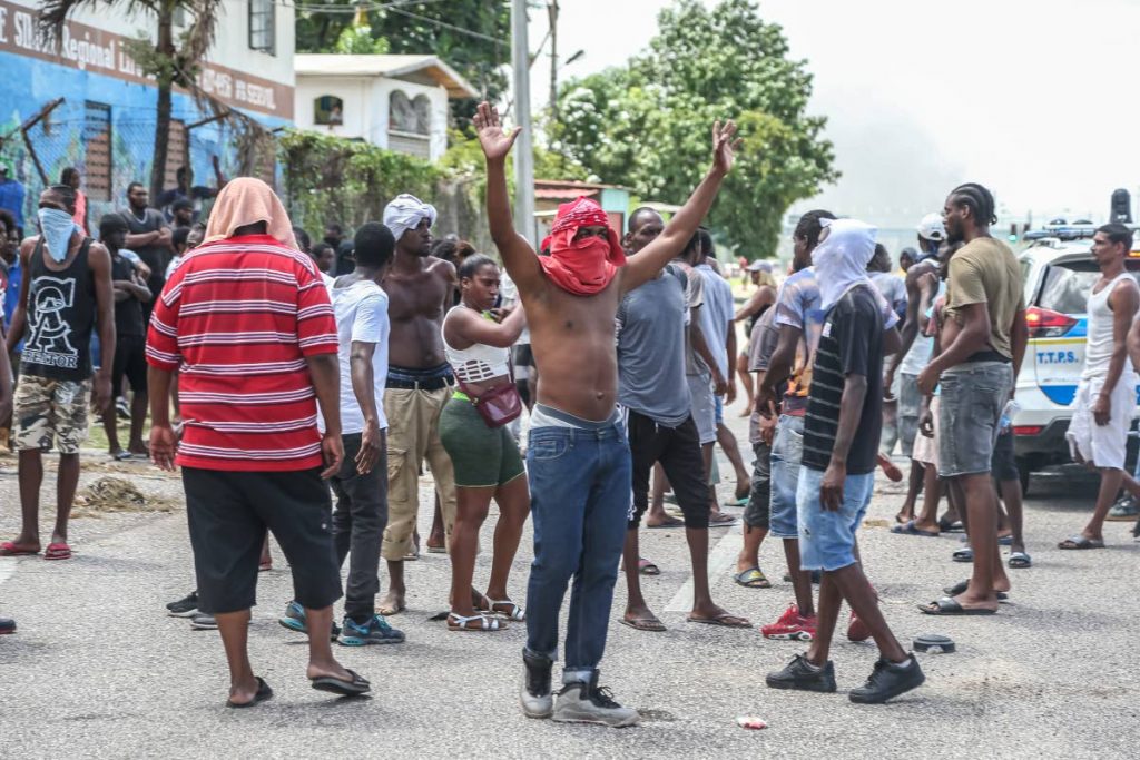 A young man raises his arms, a sign of “don’t shoot’ to police during protests in east Port of Spain over the police killing of three men in Morvant on June 25.
 PHOTO BY JEFF MAYERS - 