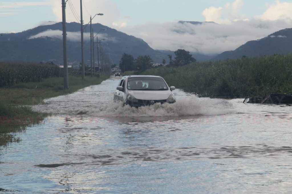 Motorists navigate flood waters along connector road in Chaguanas due to a heavy downpour this afternoon. - Lincoln Holder