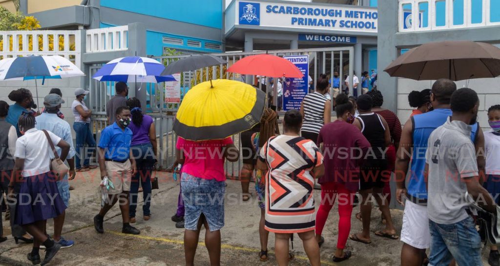 NERVOUS WAIT: Anxious parents and guardians wait in the rain for students to finish write SEA on August 20 at the Scarborough Methodist Primary School. - DAVID REID