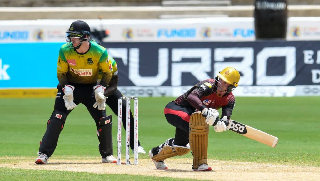 Trinbago Knight Riders' Colin Munro hits a four as Jamaica Tallawahs wicketkeeper Genn Phillips looks on  during Match 21 of the Hero Caribbean Premier League at Brian Lara Cricket Academym Tarouba, on Tuesday. - CPL T20 via Getty Images