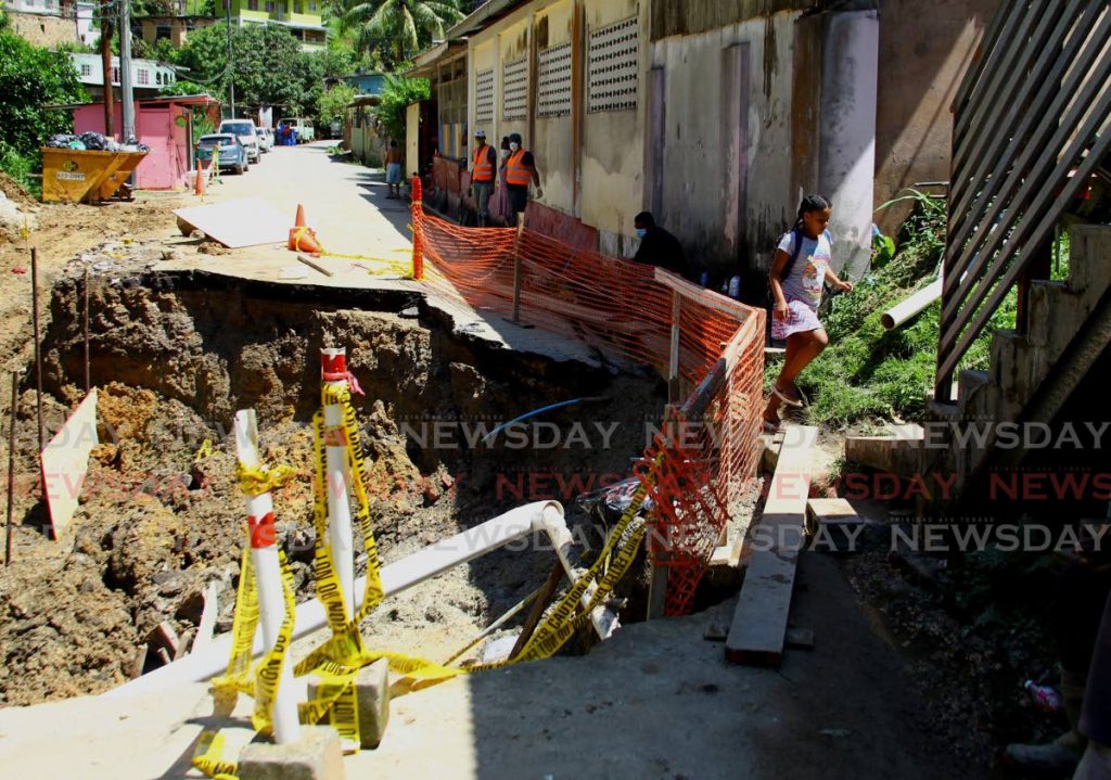 DANGEROUS PASSAGE: A child runs along the temporary pathway which is the only access for residents in the area as workmen continue restoration work on the La Seiva Main Road in Maraval on Tuesday.
 - ROGER JACOB