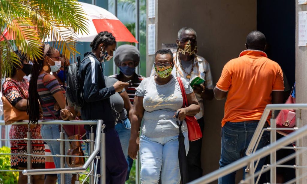 Customers wear masks as they wait in a line outside Scotiabank, Gulf City mall, Lowlands, Tobago, last Wednesday. - DAVID REID