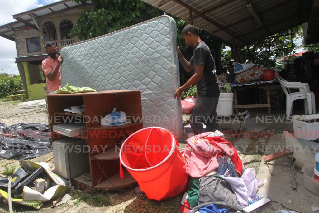 Rayon Deonarine and Ryan Ramcharitar discard a mattress and other household items which were destroyed when heavy showers caused flooding at Gopaul Avenue in Gasparillo on Thursday. - Lincoln Holder