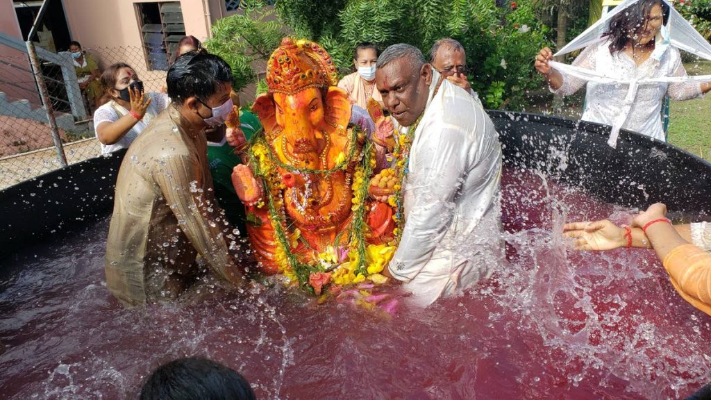 President of the Felicity Ganesh Utsav Festivals Committee, Ganesh Ragoonanan right and PRO Vishesh Singh submerge Lord Ganesh in a pool of water for the festival. - Courtesy the Felicity Ganesh Utsav Festivals Committee