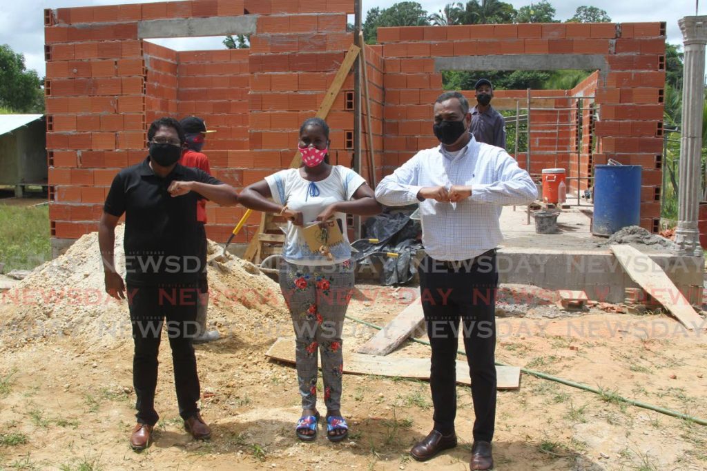 Rahim Mohammed, executive manager corporate services Angostura stand tall with Meera Boodram, the recipient of the construction of a new home and Glen Mahabirsingh, general manager operations, Coosal's during a visit to the site at Wilson road Penal. - Lincoln Holder