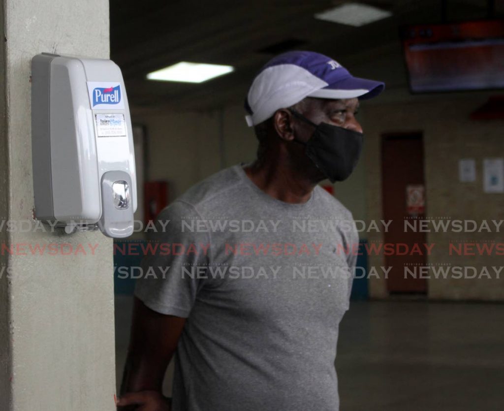 A man stand near one of two hand sanitisers at the PTSC terminal, City Gate, Port of Spain on Friday. - Angelo Marcelle