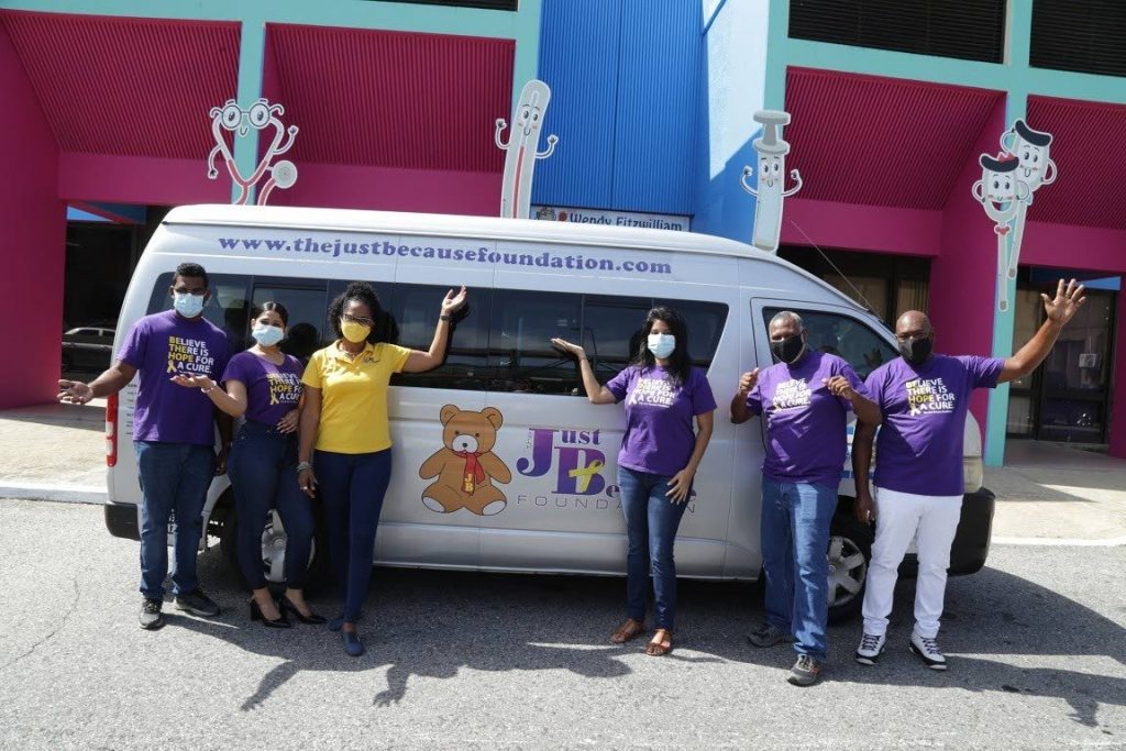 The Just Because Team stand in front of one of its vehicles used to transport cancer 
patients and their families to and from the hospital. - 