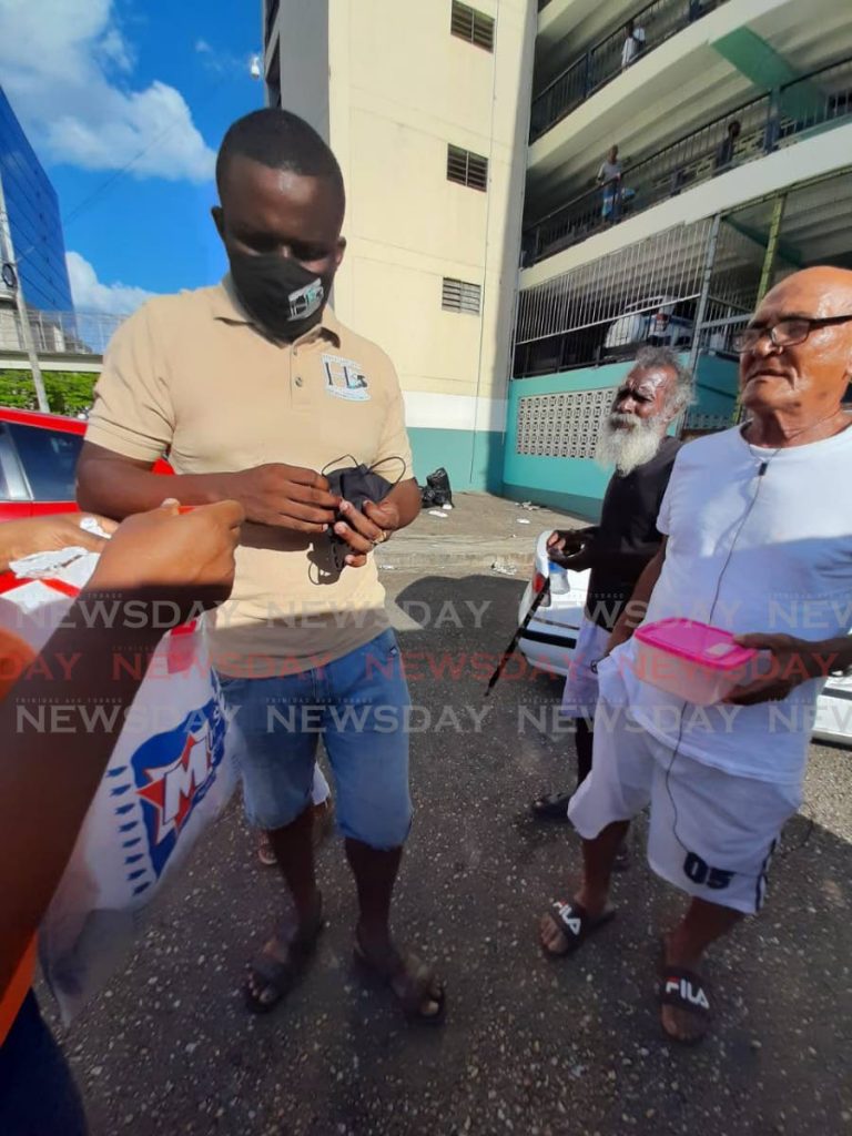 MASK TIME: Morvant businessman, David Hartman, left, distributes masks on the weekend in east Port of Spain 
Hartman is calling on other businesses to do their part in assisting the less fortunate in TT.  - Shane Superville