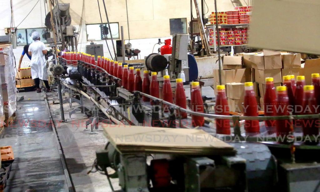 Bottles of tomato ketchup move along the production line for packaging for export at Mega Foods, O'Meara Road, Arima. PHOTO BY SUREASH CHOLAI - 
