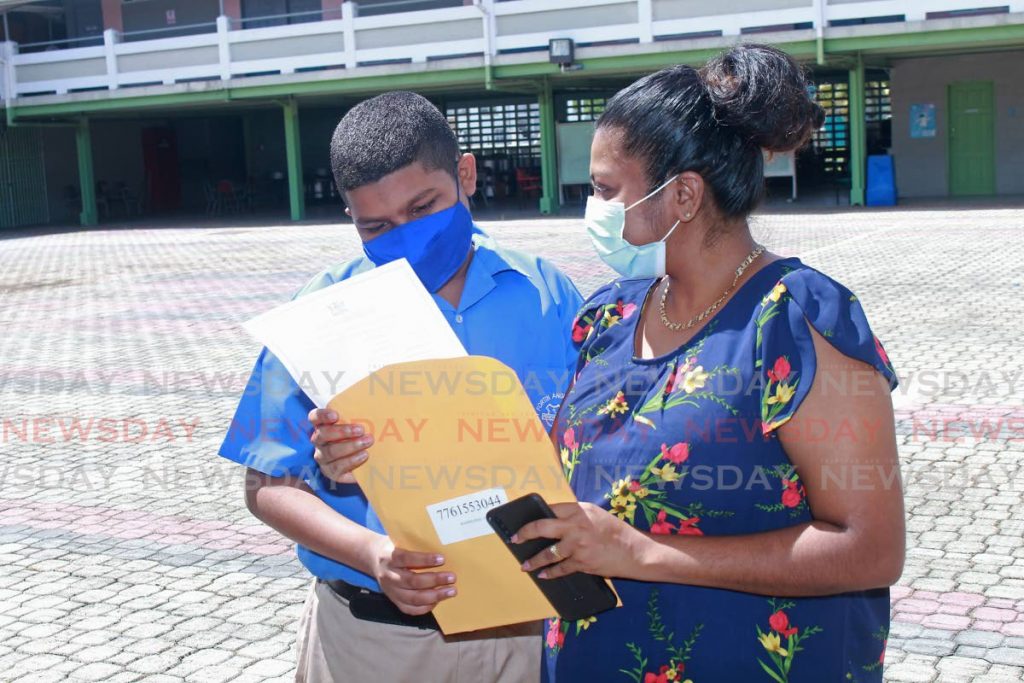 Point Fortin Anglican student Jerel Rogers and his Mother Janelle Ramdass check his S.E.A results before leaving school on Thursday morning. - CHEQUANA WHEELER