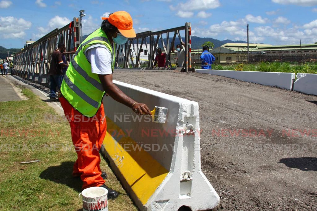  Finishing works almost completed,
Gregory Roberts an employee of the Ministry of Works and Transport, puts a fresh coat of paint on the concrete barrier, as work crews complete the installation of a Bailey Bridge to allow the flow of traffic, where motorist have been restricted from crossing due to a major collapse roadway surface, on the Arouca River Bridge, that occurred last Tuesday night,
Golden Grove Road in Arouca
Monday, October 19, 2020. - ROGER JACOB