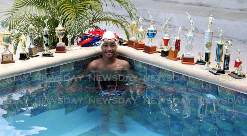 Anpherne Bernard poses with medals and trophies he has won in local and regional championships. He currently holds the national records for the 100m breaststroke, with a time of 1:20.96, and the 50m breaststroke, with a time of 37.70 second, both in the boys 9-10 category. - 