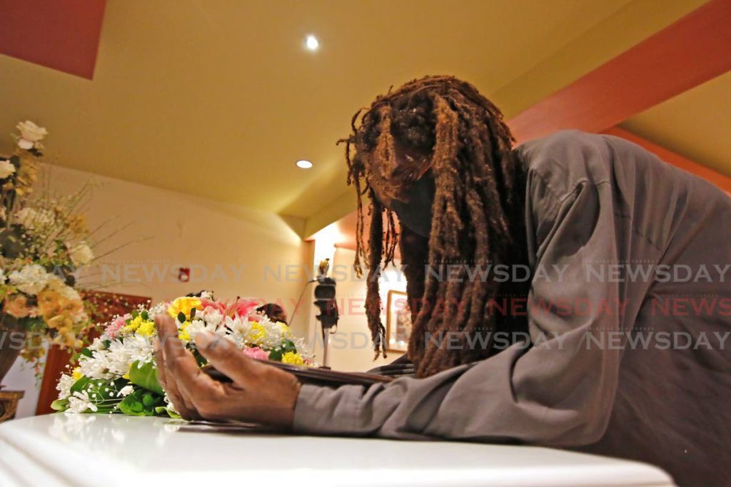 Niel Cupid mourns, placed a photo at the top of an enclosed casket with the body of his 23 year old daughter, Tineil Shanice Cupid, during the funeral service at  J.E. Guide Funeral Home, on Tuesday afternoon.  - Marvin Hamilton