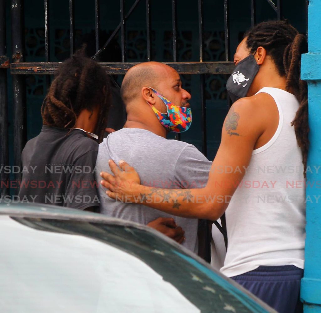 SORROW: A relative (centre) of shooting victim Allan Stoute is consoled at the family’s home in Arima on Thursday.  - ROGER JACOB