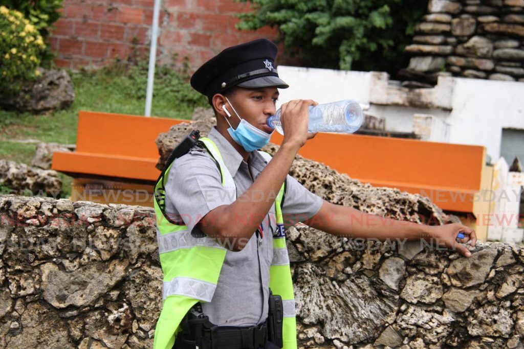 PC Gabriel Sayers keeps himself hydrated by drinking water while on duty on Jermingham Street, Scarborough, Tobago. -File photo Ayanna Kinsale 