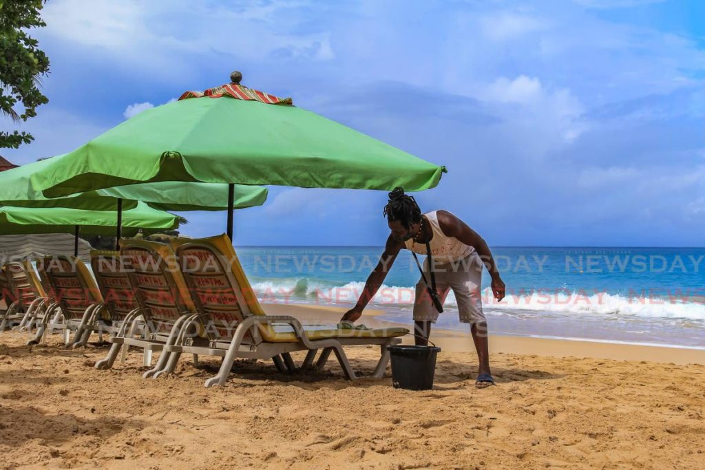 Owner of Dimples Rentals, Liston Cox cleans his beach chairs at Store Bay on Monday morning in preparation for beachgoers. The Prime Minister announced the reopening of beaches in a media conference on Saturday. PHOTO BY AYANNA KINSALE - 