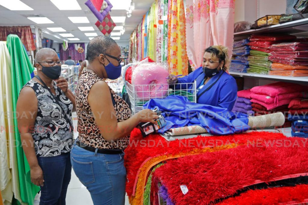 A Home Land Furnishings & Fabric Land store supervisor (Blue blazer) attendeds to customers for their Christmas shopping on High Street San Fernando, on Monday afternoon. - Marvin Hamilton