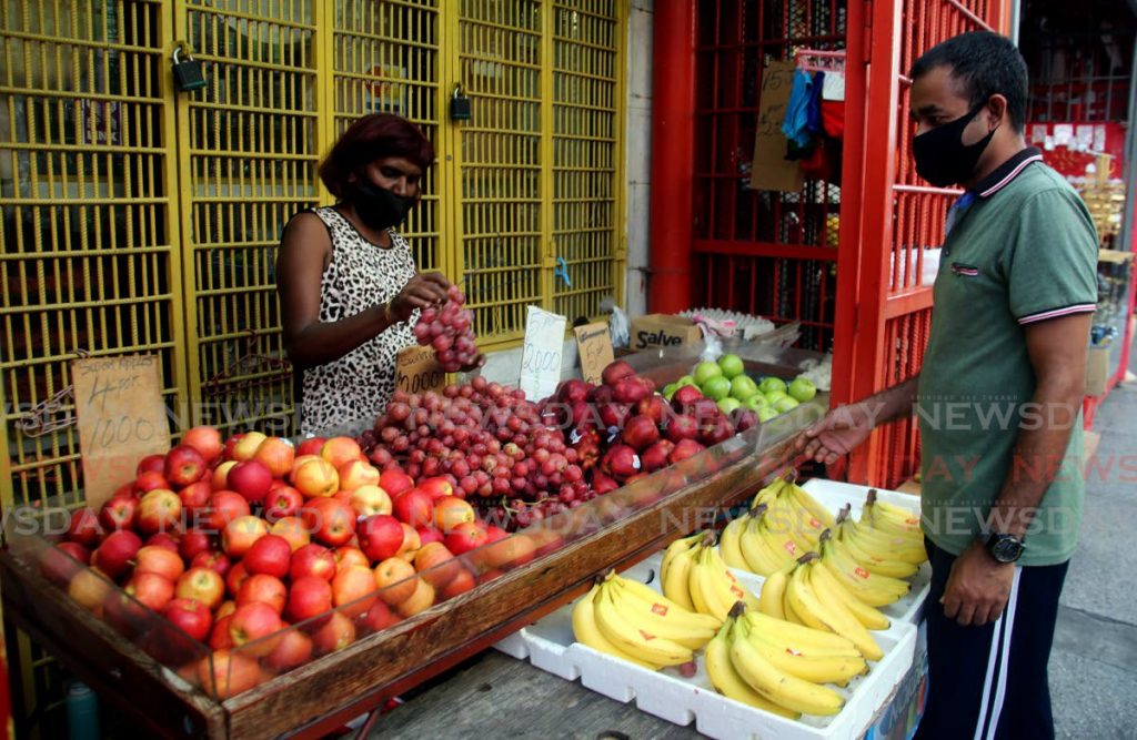 FRESH SUPPLIES: Fruit vendor Gaitree Doodnath attends to a customer on Tuesday from her stall on Charlotte Street in Port of Spain. 
 - SUREASH CHOLAI