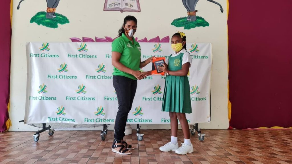 First Citizens Clarke Road United representative and former Sri Lanka women's cricketer Sandamali Dolawatta distributes a tablet to a student of Clarke Road Hindu School. - 