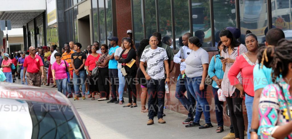 In this March file photo, people stand in line on the pavement waiting to conduct business at a bank in Port of Spain. Startup QKYC wants to help streamline the KYC (know your customer) process for banks and customers. - SUREASH CHOLAI