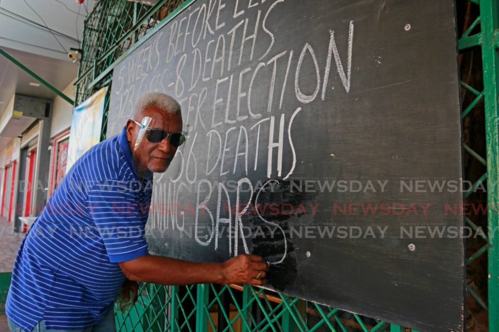 In this September 15, 2020 file photo, Allan Campbell, owner of Carrat Shed bar in Marabella, writes a message of protest against the restrictions on how bars operate. On Thursday, the Prime Minister announced that bars and restaurants would close until May 23.
