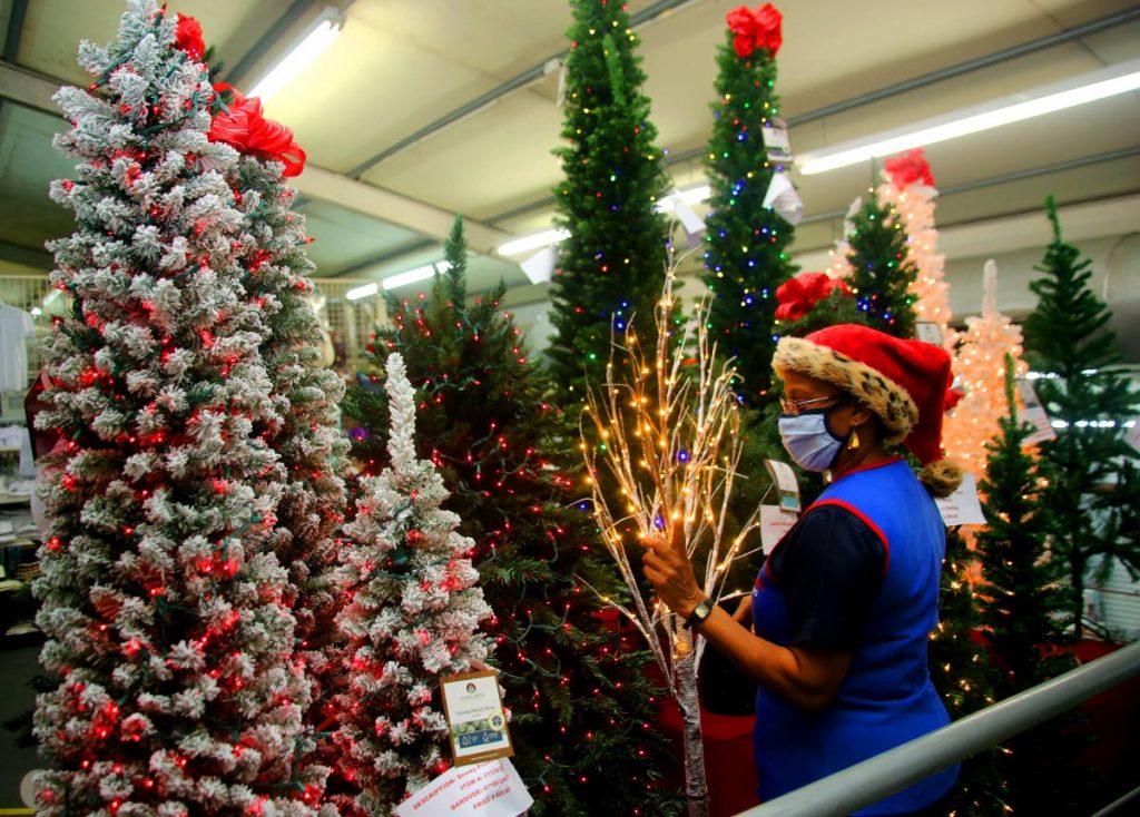 Sharon Clement makes sure the Christmas trees on display for sale look the best at Excellent Stores in Excellent City Centre, Frederick Street , Port of Spain. - SUREASH CHOLAI