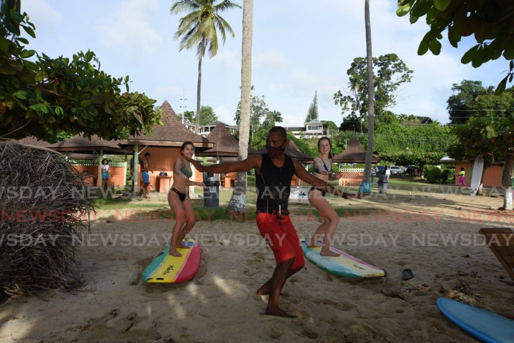Adriana Hall, left, and Isabelle Smyth learn a surf technique from owner of Surf Tobago Alvin Luke at Mt Irvine Bay last month. PHOTO BY AYANNA KINSALE  - 