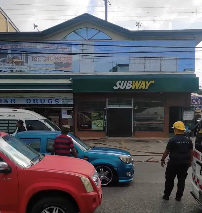 A screenshot from a Facebook video shows fire officials at the site of a fire at Subway's Point Fortin branch.  