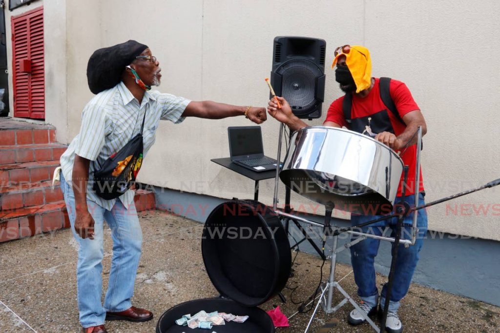 Sound of apporval: A passerby greets pannist Allan Cardinal on High Street, San Fernando on Friday afternoon. Cardinal serenaded the street with Christmas carols. - Marvin Hamilton