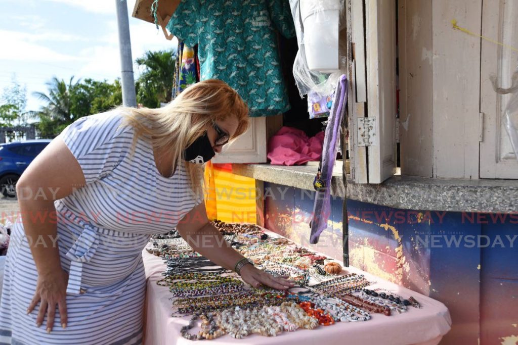 A customer examines jewellery at a vendor's stall at Store Bay, Tobago. Caricom countries could not agree on protocols for a travel bubble in the region, the Prime Minister said on Saturday. PHOTO BY AYANNA KINSALE - 