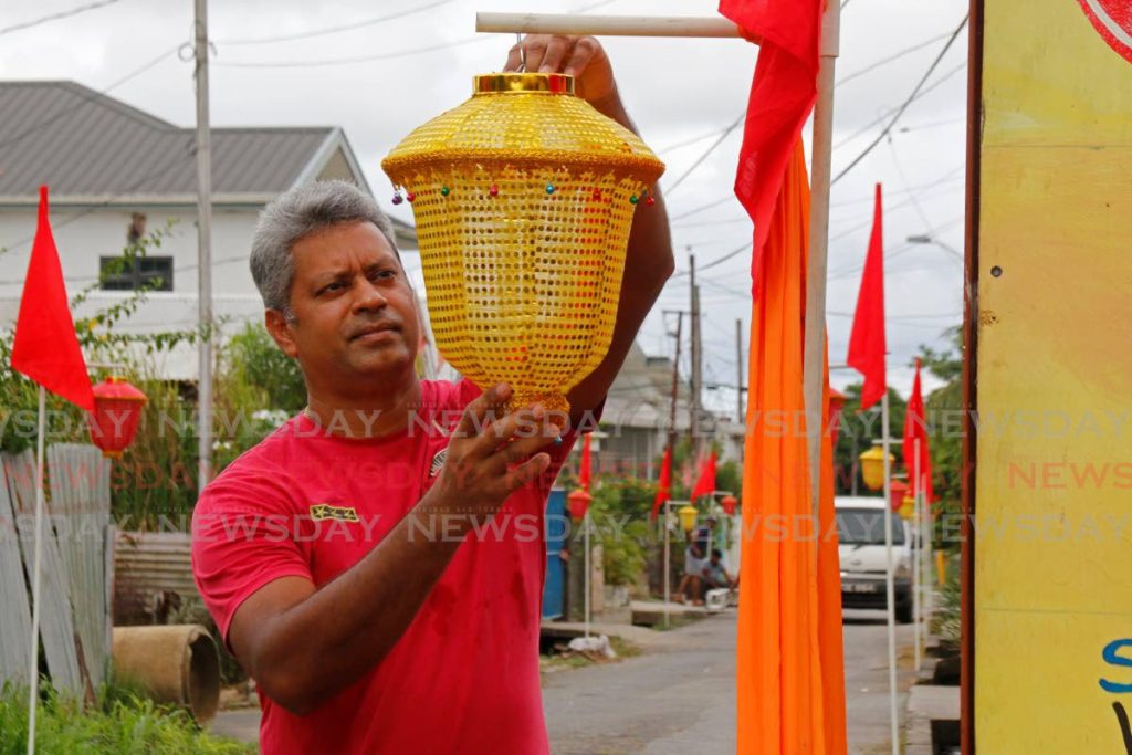 Lyle Street resident Navin Heerman attaches a lantern to a decorated pole for Divali celebrations in Felicity on Saturday. - 